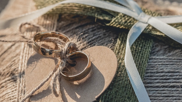 Free photo closeup shot of golden wedding rings attached to a brown heart-shaped textile