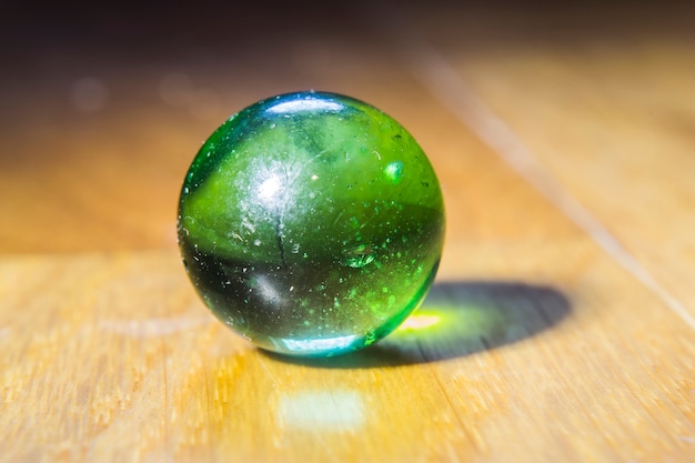 Closeup shot of a green marble on top of a wooden table