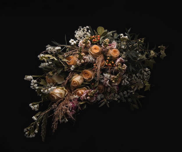 Free Photo closeup shot of a luxurious bouquet of orange and brown roses on a black background