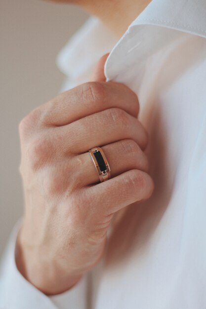 Closeup shot of a male in a formal outfit wearing a golden ring