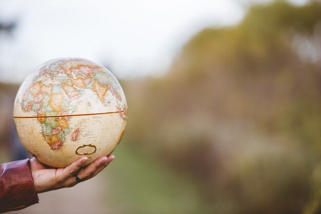 Closeup shot of a male holding a desk globe with a blurred background