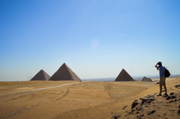 Free photo closeup shot of a male standing and looking at giza necropolis in egypt