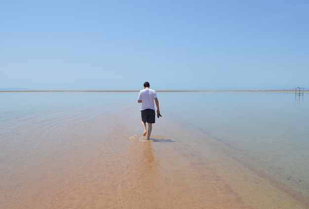 Closeup shot of a male walking on the beach on a sunny day