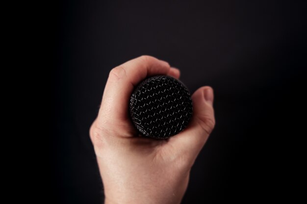 Free photo closeup shot of a microphone in the hand of a person on black