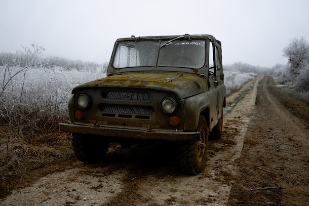 Free photo closeup shot of an old car on the road surrounded by winter trees