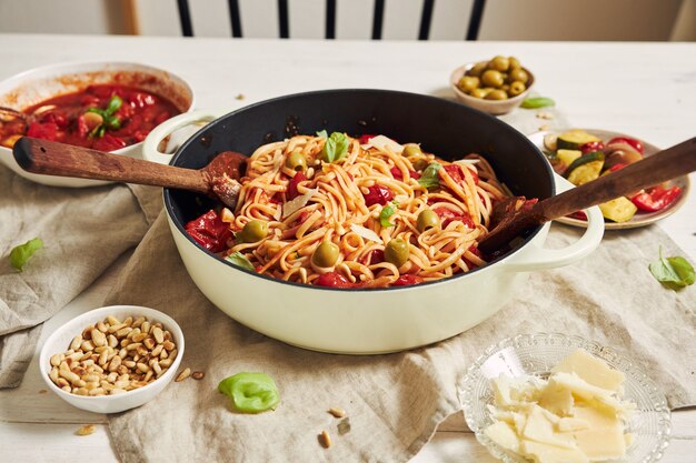 Closeup shot of pasta with vegetables and ingredients on a white table