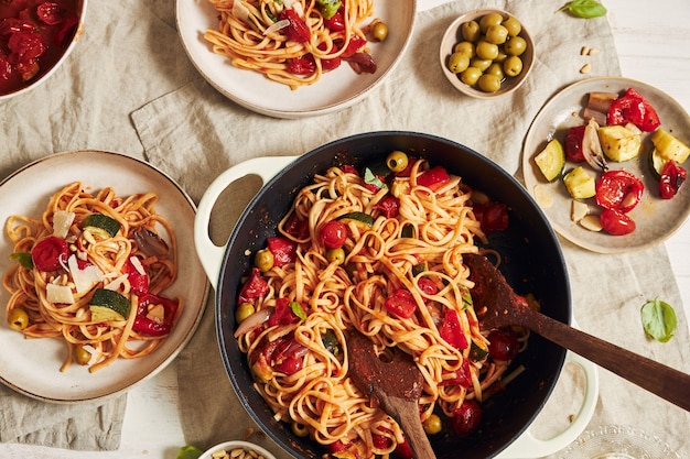 Closeup shot of pasta with vegetables and ingredients on a white table