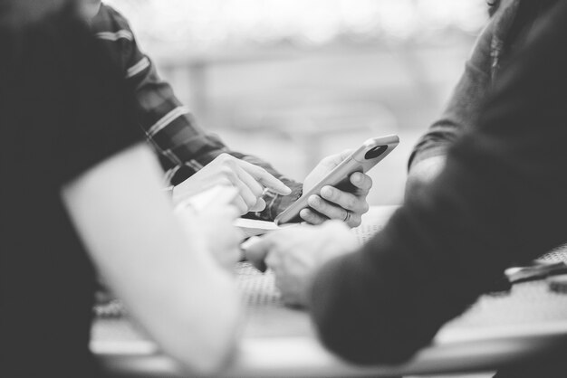 Closeup shot of people using their smartphone with a blurred background in black and white