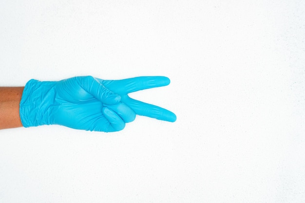 Closeup shot of a person hand in blue medical gloves showing a sign by hands near a copy space