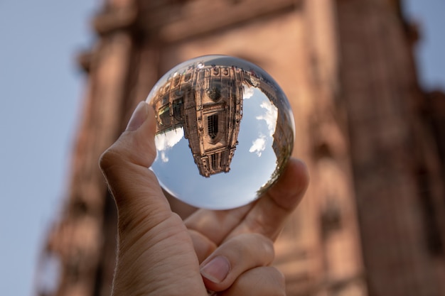 Closeup shot of a person holding a crystal ball with the reflection of historic buildings