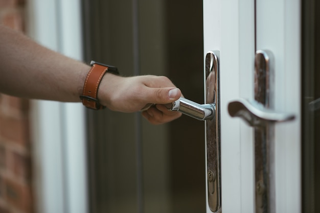 Free photo closeup shot of a person holding a door knob and opening the door