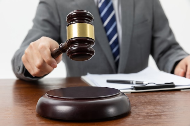 Free photo closeup shot of a person holding a gavel on the tabl