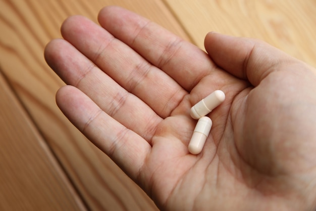 Free Photo closeup shot of a person holding two capsules on the palm of his hand