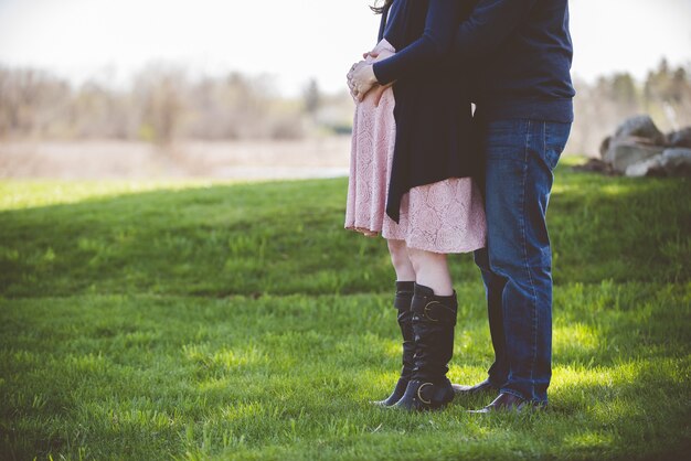 Closeup shot of a pregnant couple standing on a grassy field