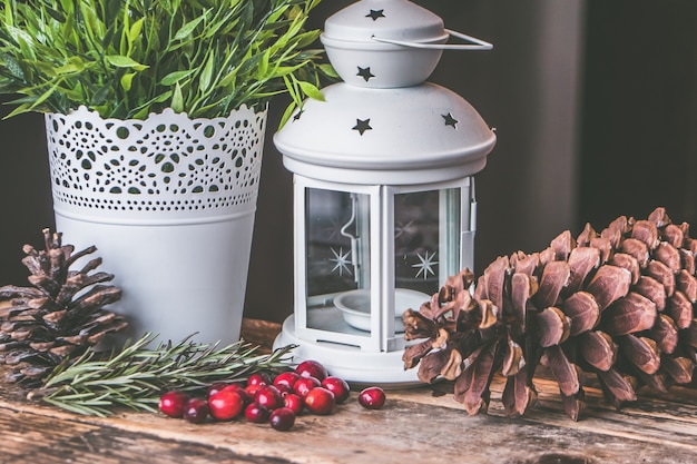 Free Photo closeup shot of red coffee beans and a pinecone with a candle lantern on a wooden surface