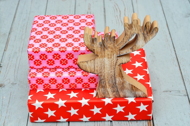 Closeup shot of red gift boxes stacked on top of each other  and a wooden reindeer figure