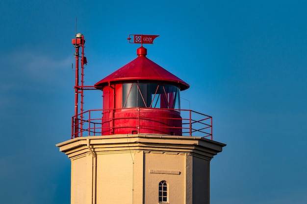 Closeup shot of a red and white tower behind a blue sky