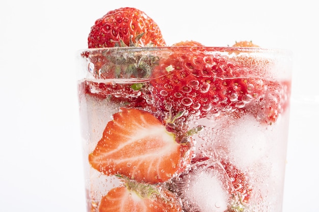 Free photo closeup shot of a refreshing drink with a slice of strawberries and ice cubes