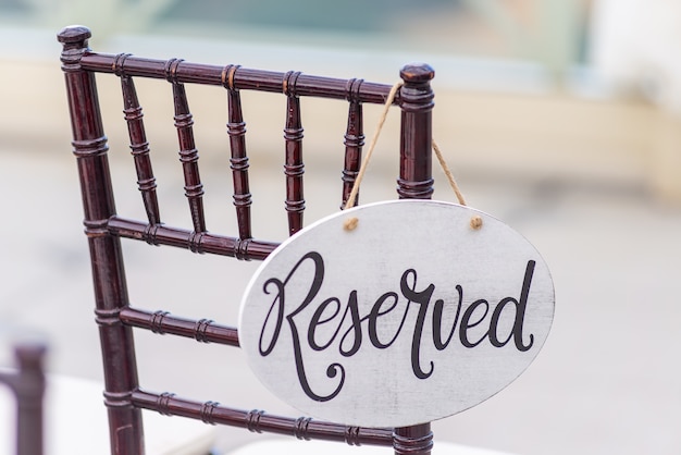 Free photo closeup shot of a reserved sign hanging on a chair at a wedding ceremony