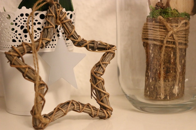 Free photo closeup shot of rustic decors of wicker star and wood with jute twine in a glass