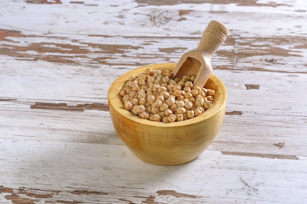 Closeup shot of a rustic wooden bowl of raw chickpea (Cicer arietinum)