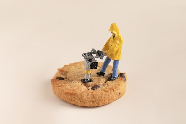 Free Photo closeup shot of a small construction worker working on a chocolate cookie