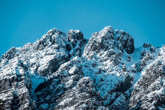 Free Photo closeup shot of snow covered jagged mountain peaks under clear blue skies