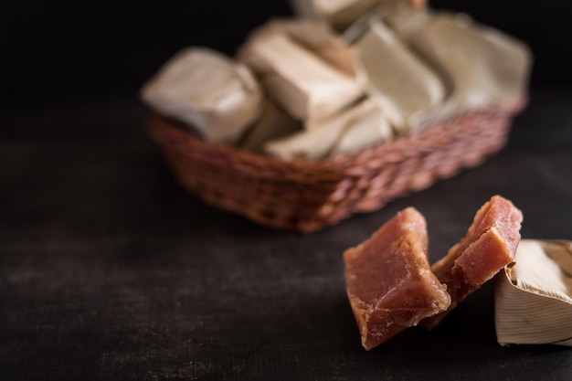 Closeup shot of sweet colombian candy covered with leaves in a little basket on a wooden table