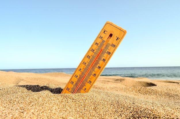 Free Photo a closeup shot of a thermometer in the beach sand