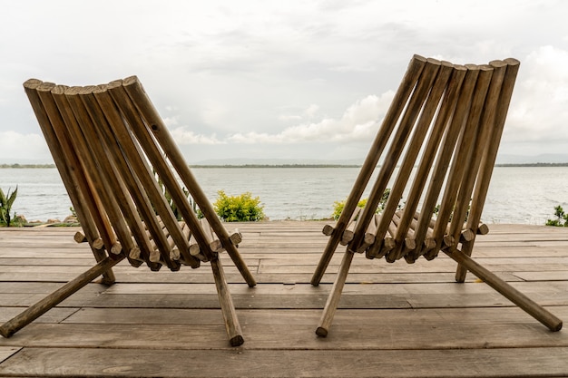 Free photo closeup shot of two chairs in front of the ocean under a cloudy sky