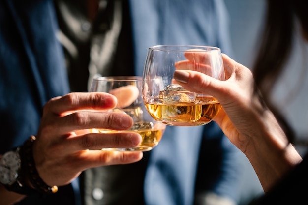 Free photo closeup shot of two people clinking glasses with alcohol at a toast