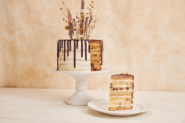 Free photo closeup shot of a vanilla cake with chocolate drip and flowers on top