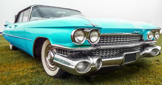 Closeup shot of a vintage turquoise car parked on a green field