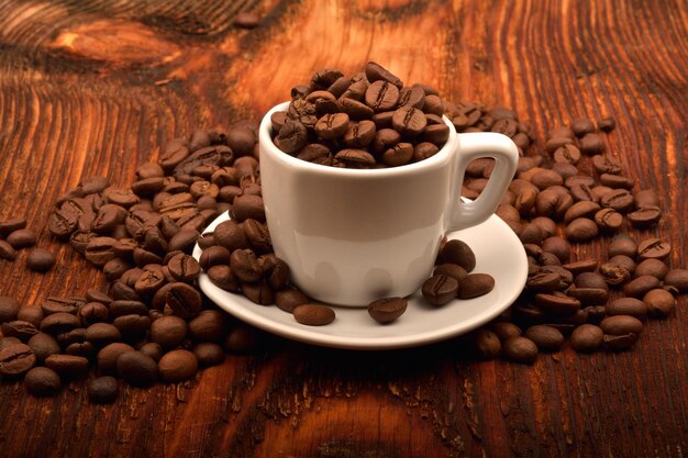 Closeup shot of a white cup full of coffee beans on a wooden table