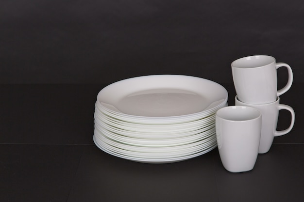 Free photo closeup shot of white plates and mugs on a black background