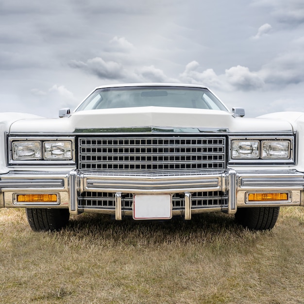 Free photo closeup shot of a white retro car parked on a dry field under a cloudy sky