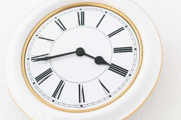 Closeup shot of a white roman numeral wall clock