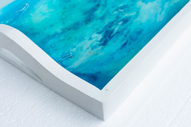 Closeup shot of a white tray with epoxy resin art with blue inks