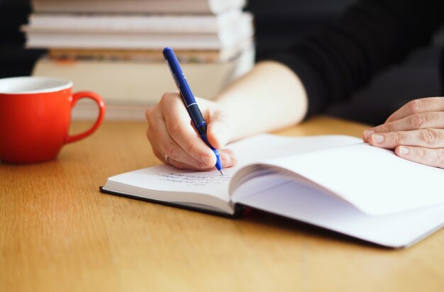 Closeup shot of a woman working or studying from home with a red coffee cup nearby