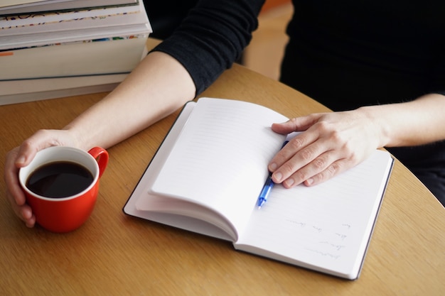 Free Photo closeup shot of a woman working or studying from home with a red coffee in her hand