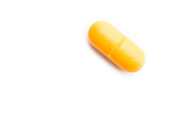 Free Photo closeup shot of a yellow pill on a white surface