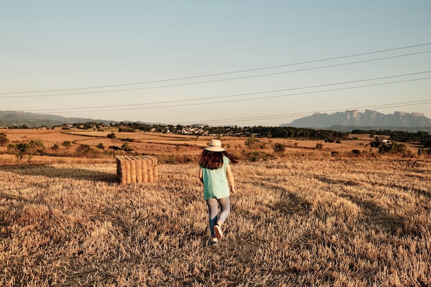 Free photo closeup shot of a young girl with a round hat walking in the field