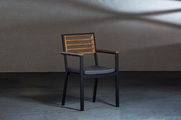 Closeup of a simple modern chair with metallic legs in a room with gray walls