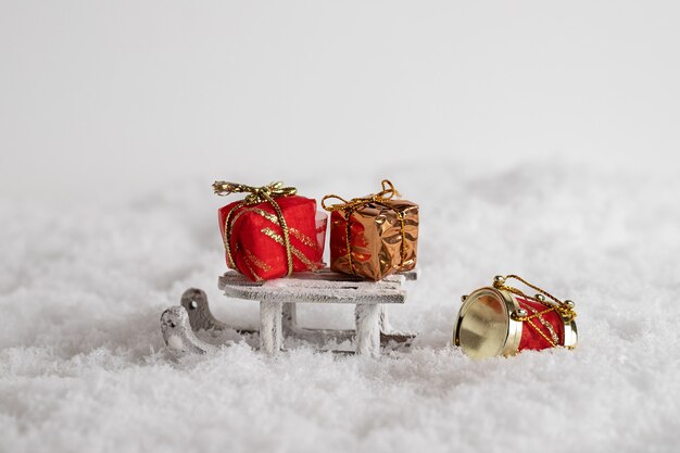 Closeup of a sleigh and colorful gift boxes in the snow, Christmas toys in the white background