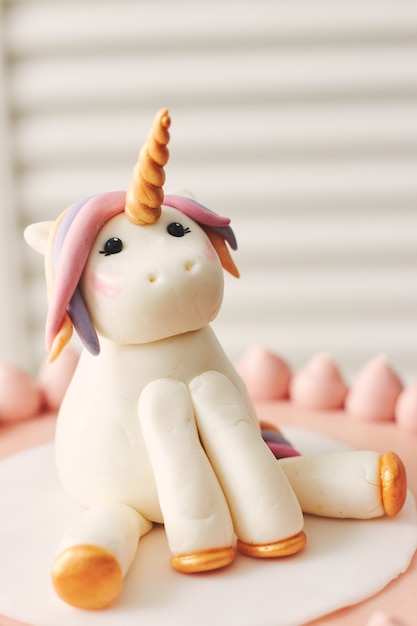 Free photo closeup of a small unicorn on the top of a birthday cake under the lights with a blurry background