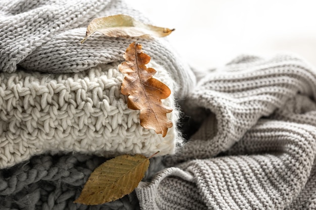 Free Photo closeup of a stack of knitted sweaters with autumn leaves