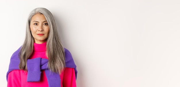 Free photo closeup of stylish woman with grey hair and no wrinkles smiling and looking at camera standing in tr