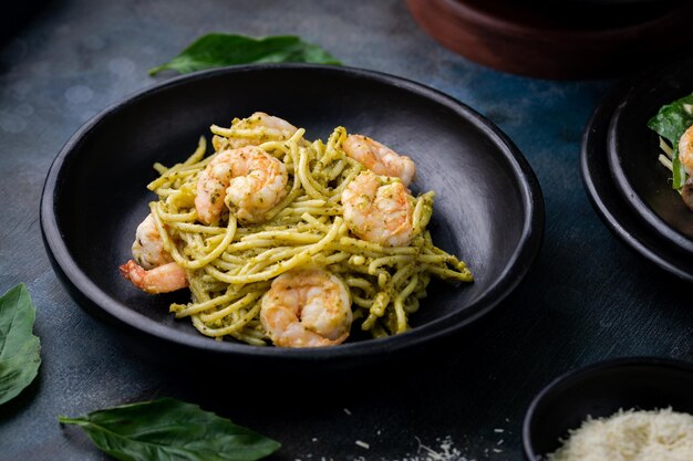 Closeup of tasty spaghetti served with freshly cooked shrimp in a black bowl