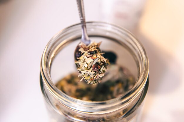 Closeup of a teaspoon and a jar of herbal tea