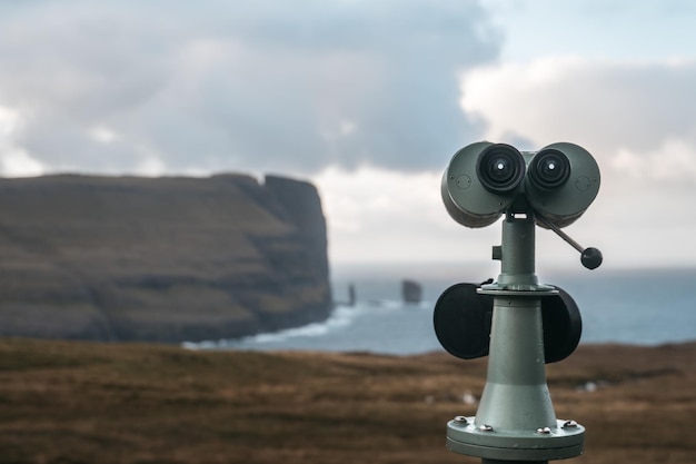 Free Photo closeup of a tower viewer on the ground surrounded by cliffs and the sea under a cloudy sky